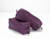 Two purple toiletry bags with gold zippers on a white background