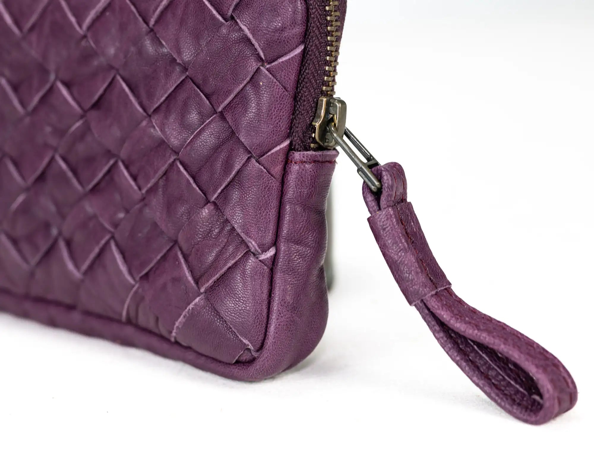Close-up of a purple quilted handbag with a strap on a white background
