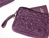 Purple leather crossbody bag with woven pattern and phone on a white background