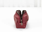 Red leather handbag with a zipper on a white background
