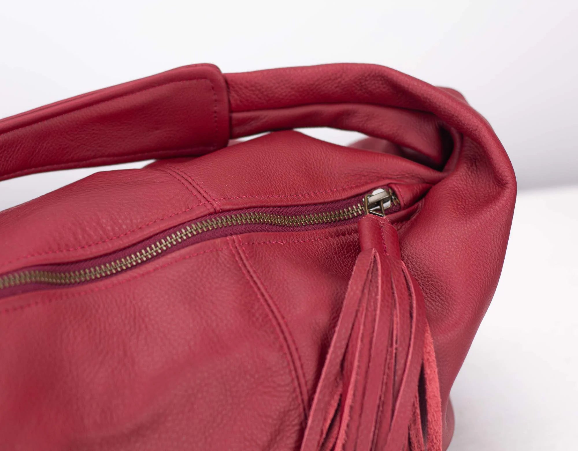 Red leather handbag with a tassel on a white background