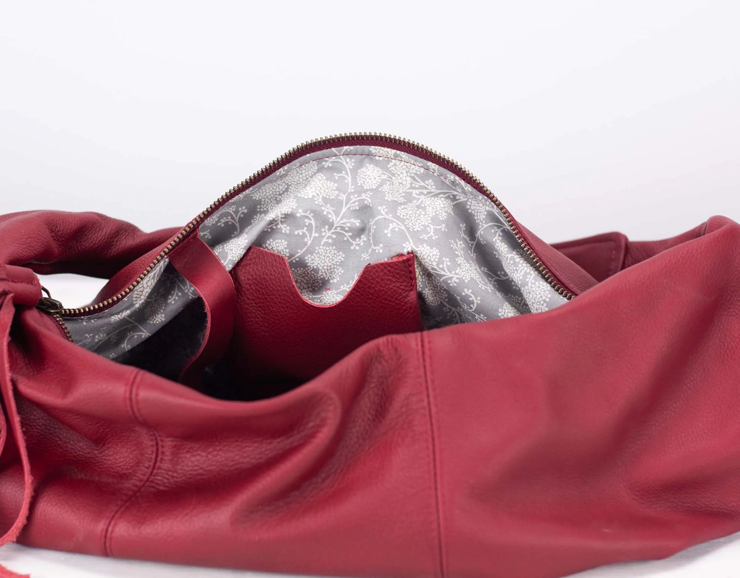 Red leather bag with a floral interior lining on a white background