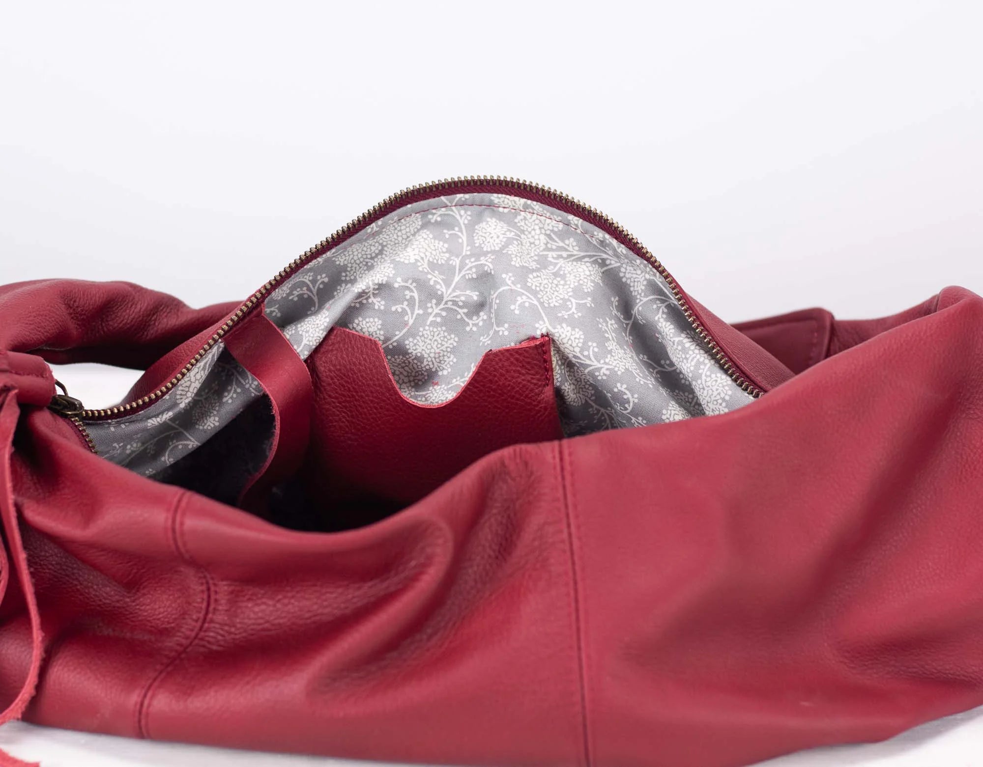 Red leather bag with a floral interior lining on a white background