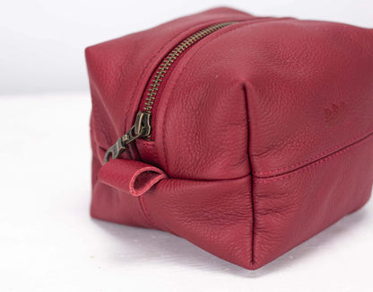 Red leather toiletry bag with gold zipper on a white background
