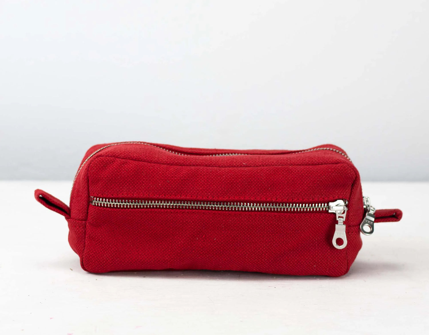 Red cotton toiletry bag with zippers on a white background