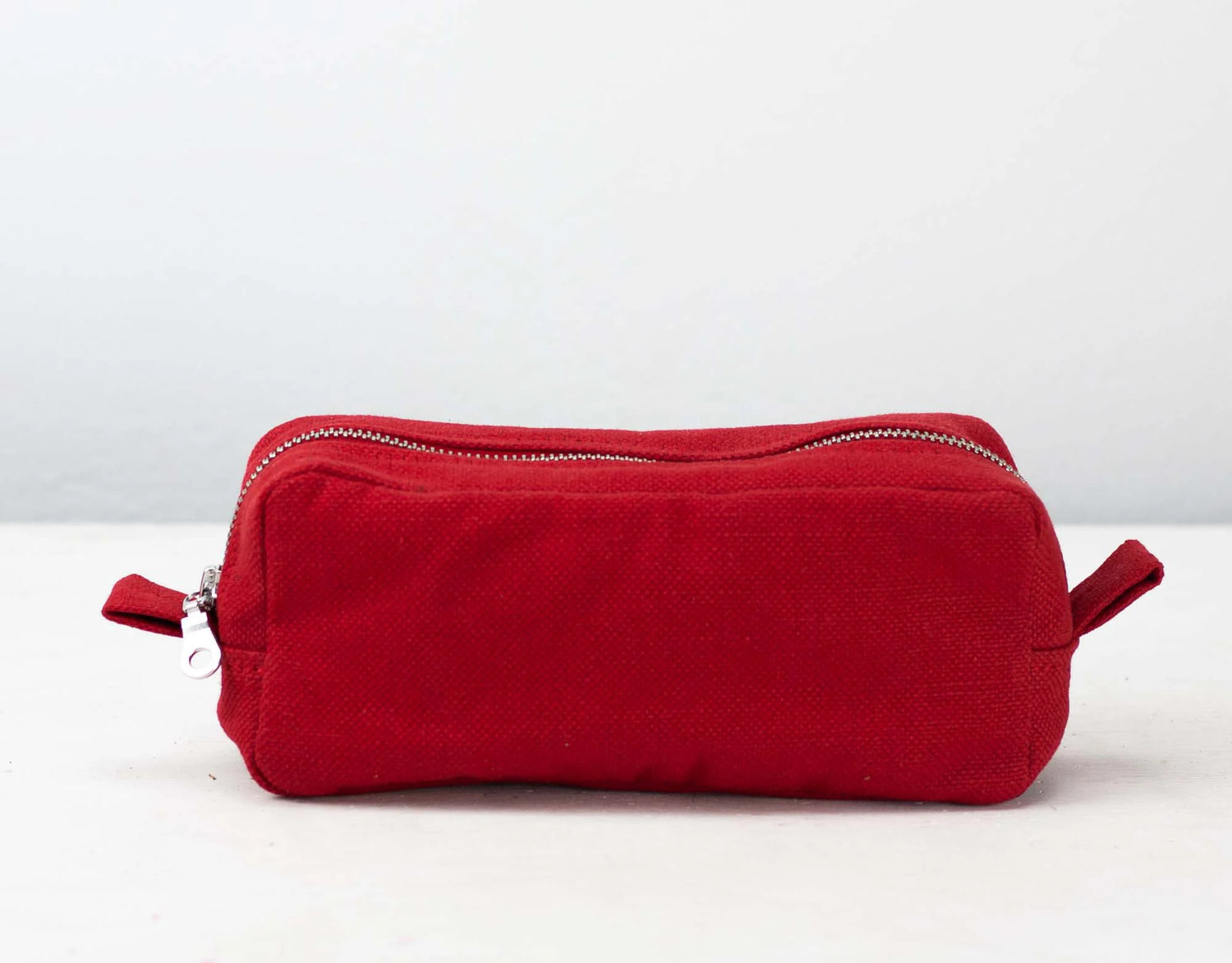 Red cotton toiletry bag with zippers on a white background