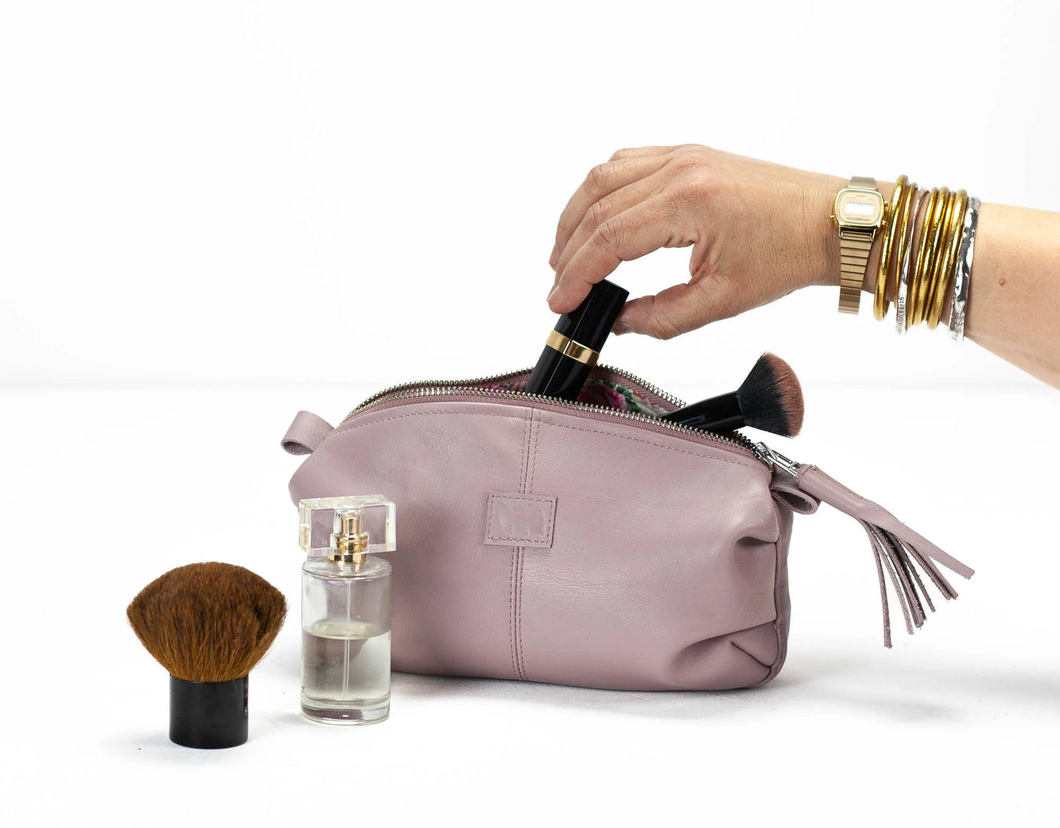 Pink makeup bag with cosmetic items on a white background