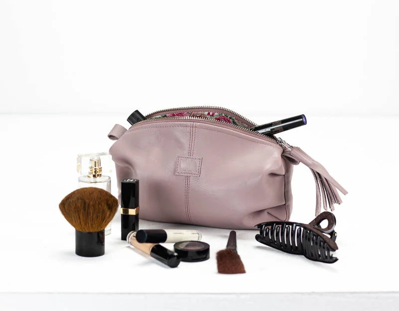 Makeup bag with various cosmetic items on a white background
