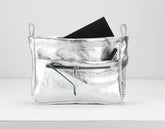 Silver clutch bag with a black phone inside on a white background