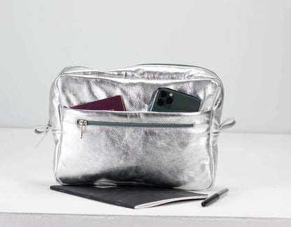 Silver pouch with phone, passport, and tablet on a white background