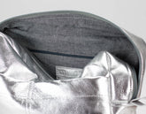 Close-up of a silver metallic pouch inside a gray bag with a visible brand label.
