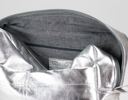 Close-up of a silver metallic pouch inside a gray bag with a visible brand label.