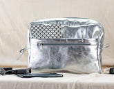Silver insert bag on a beige surface with a phone and lip gloss visible