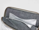 Close-up of a gray pouch with a silver lining on a light gray background