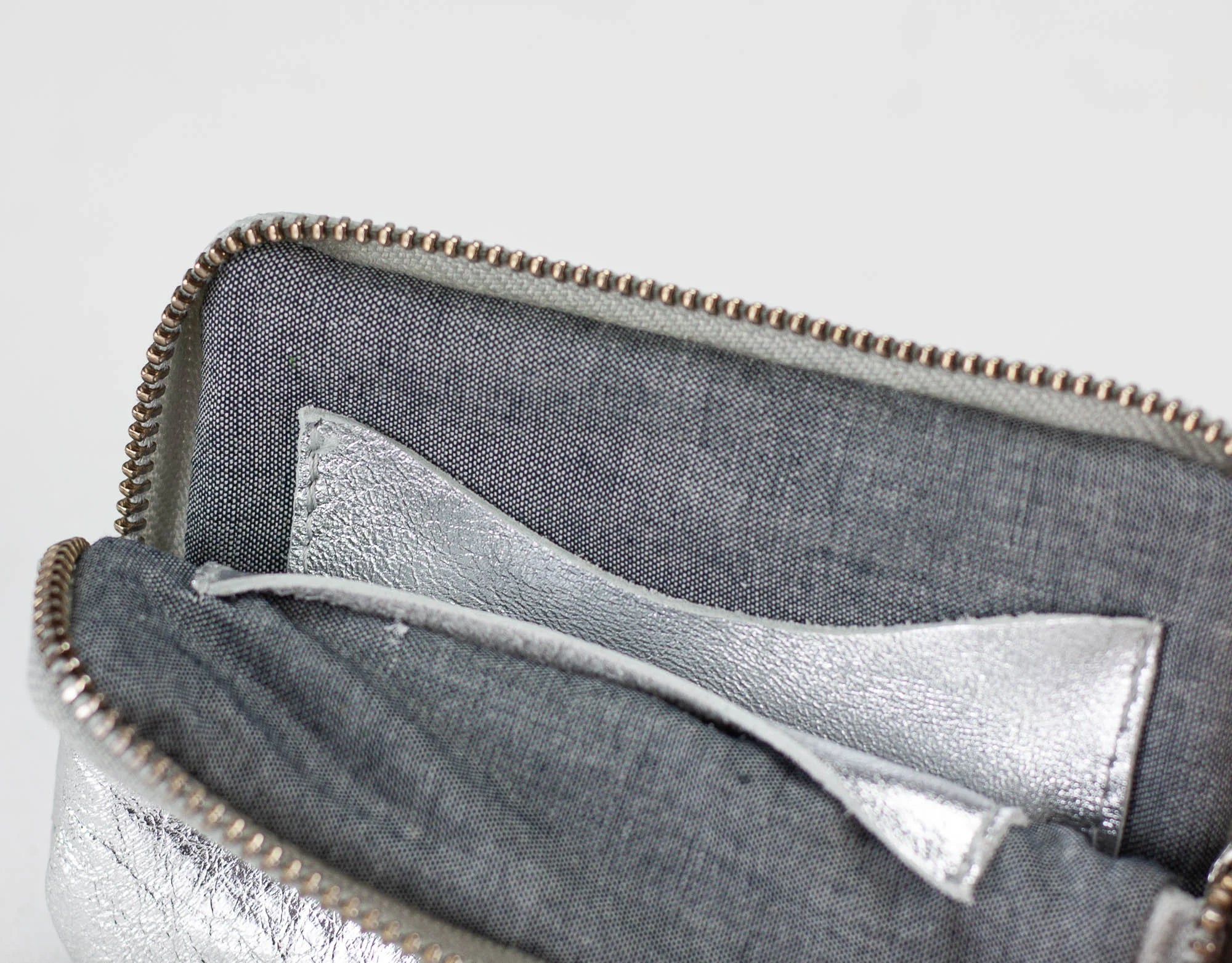 Close-up of a gray pouch with a silver lining on a light gray background