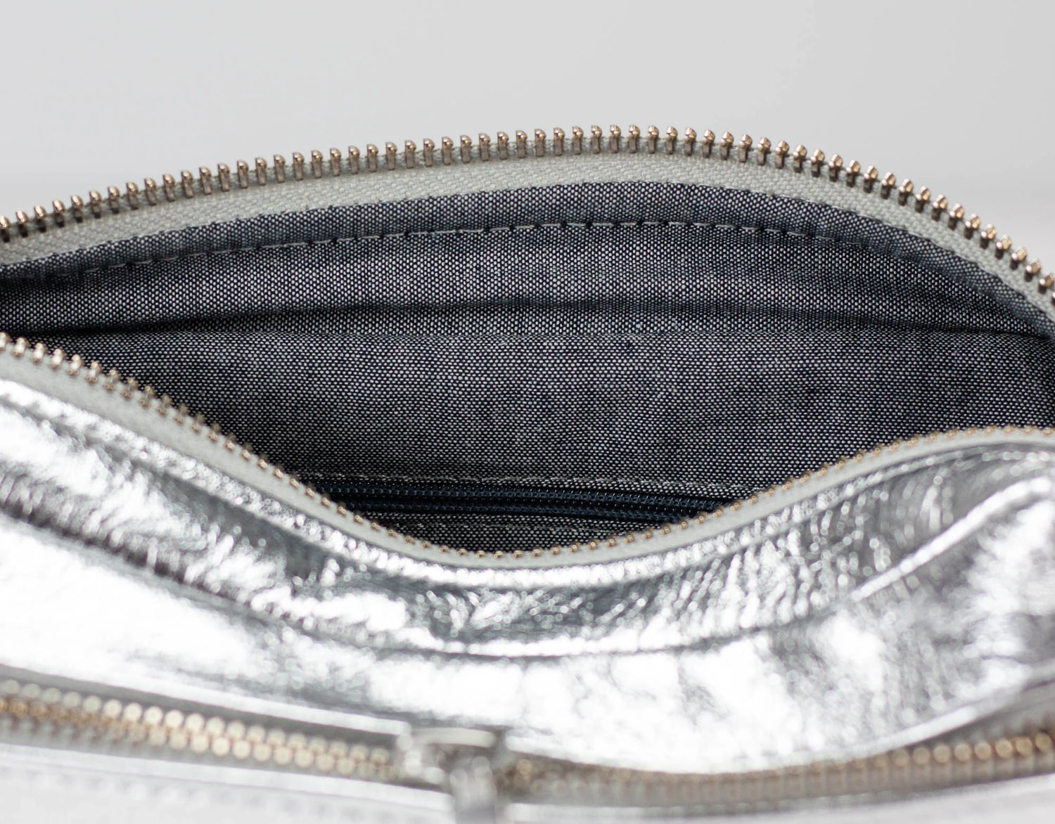 Close-up of a silver metallic pouch with a zipper, showing the interior