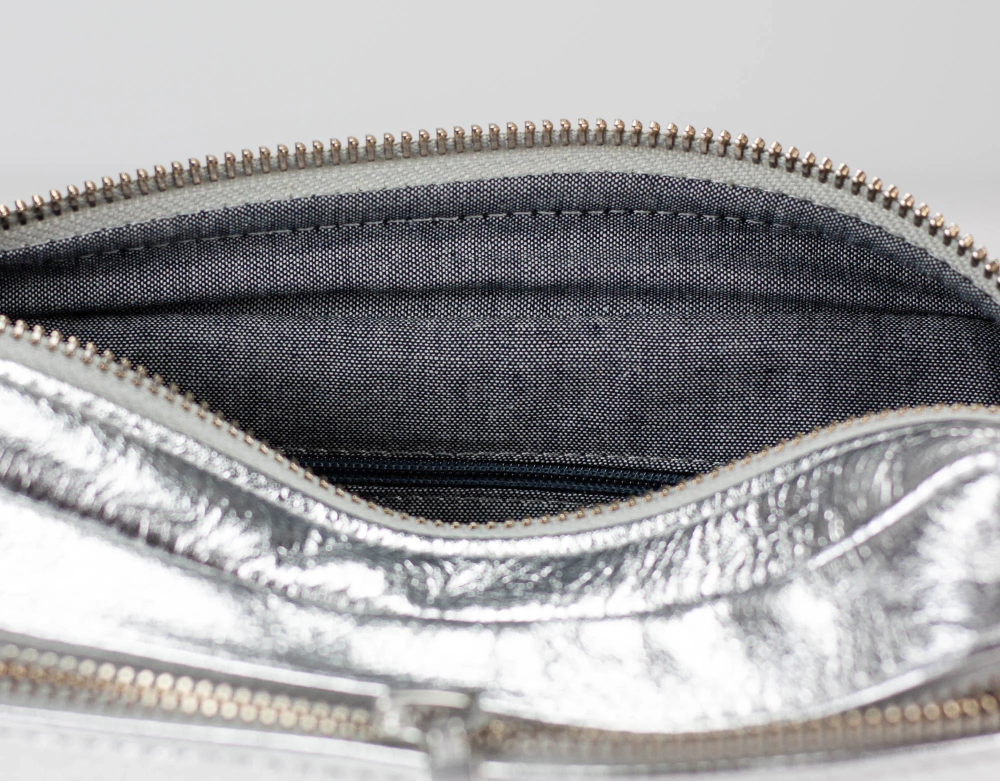 Close-up of a silver metallic pouch with a zipper, showing the interior