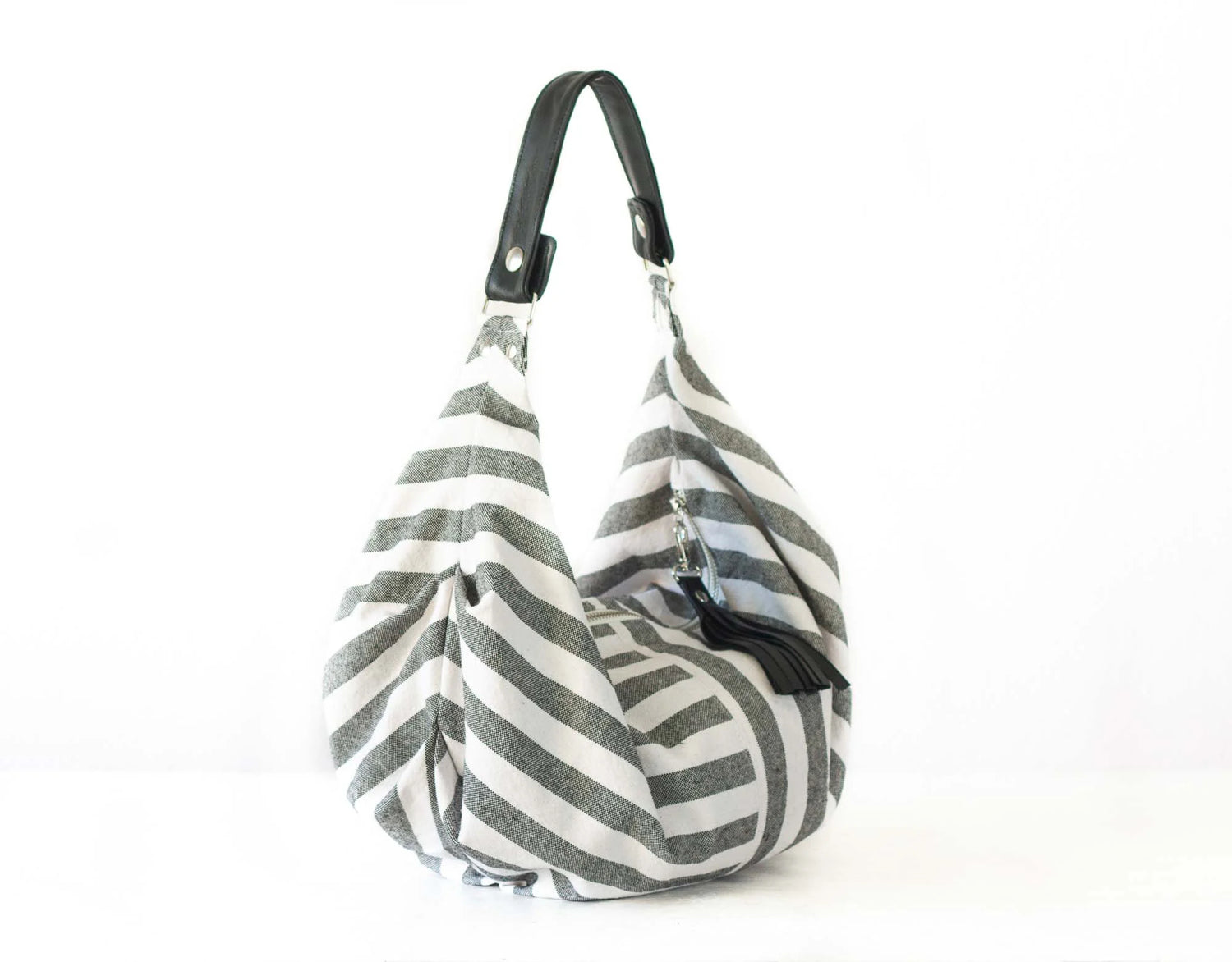 Gray and white striped bag with a black handle on a white background
