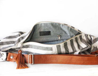 Fanny pack with striped pattern and brown leather strap on a white background