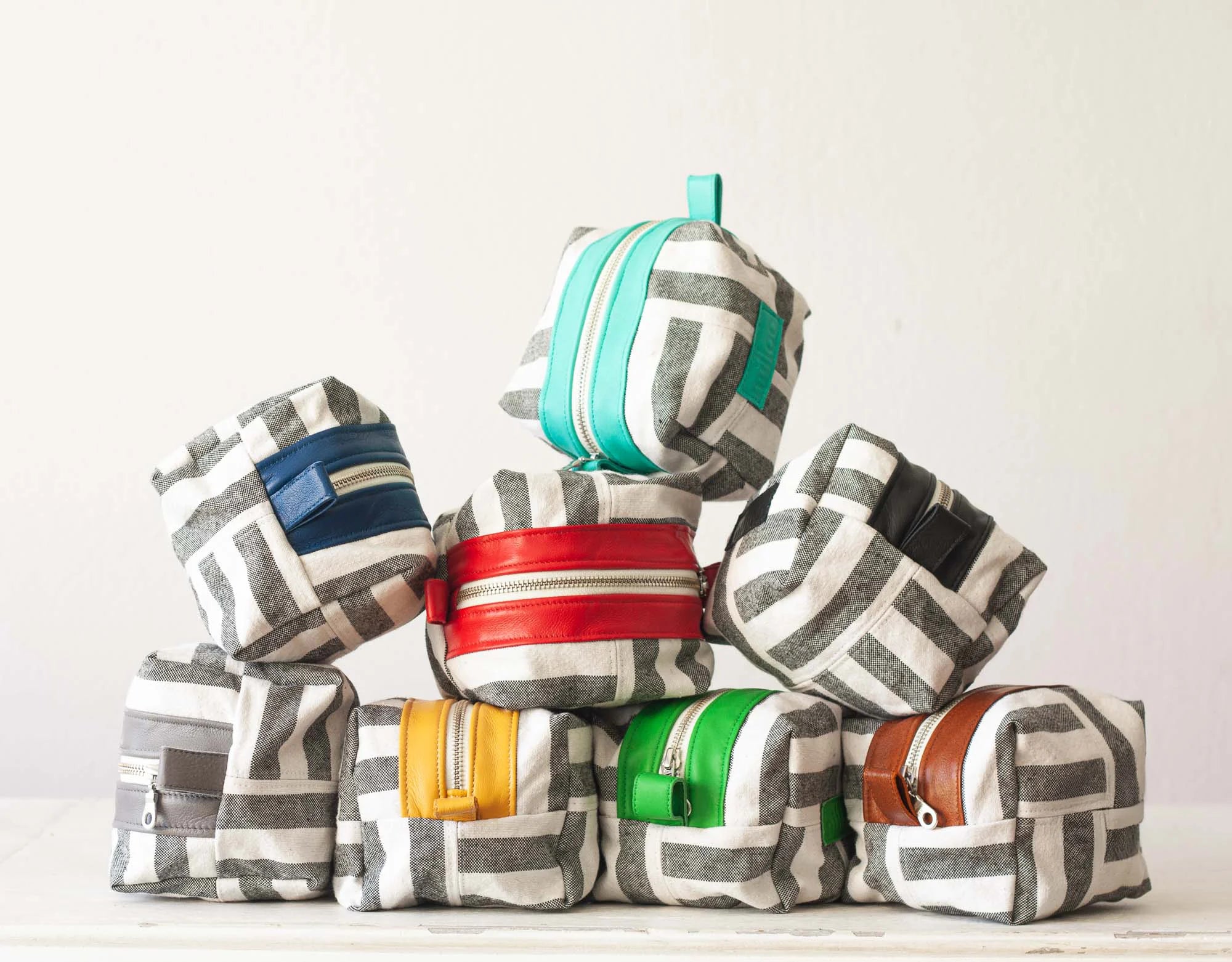Stack of colorful fabric bags with geometric patterns on a white background