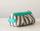 Striped pouch with teal zipper on a light background