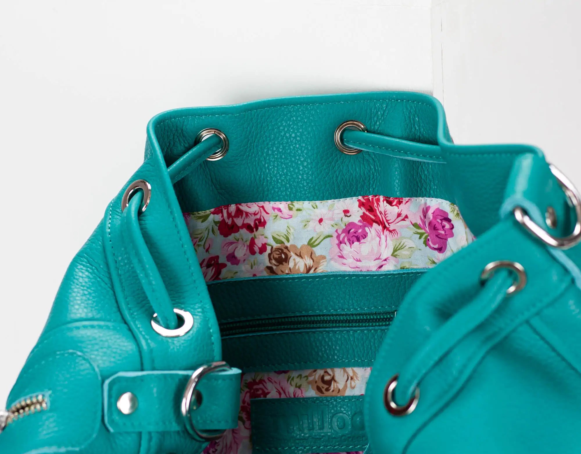 Turquoise handbag with floral interior on a white background