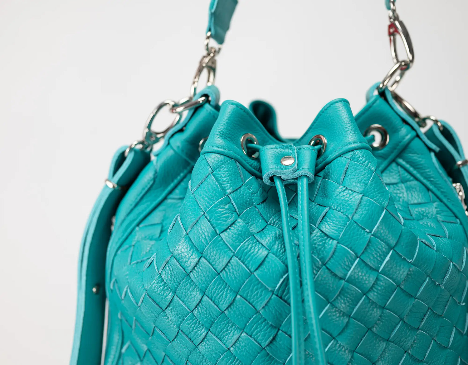 Turquoise woven handbag with drawstring on a light gray background