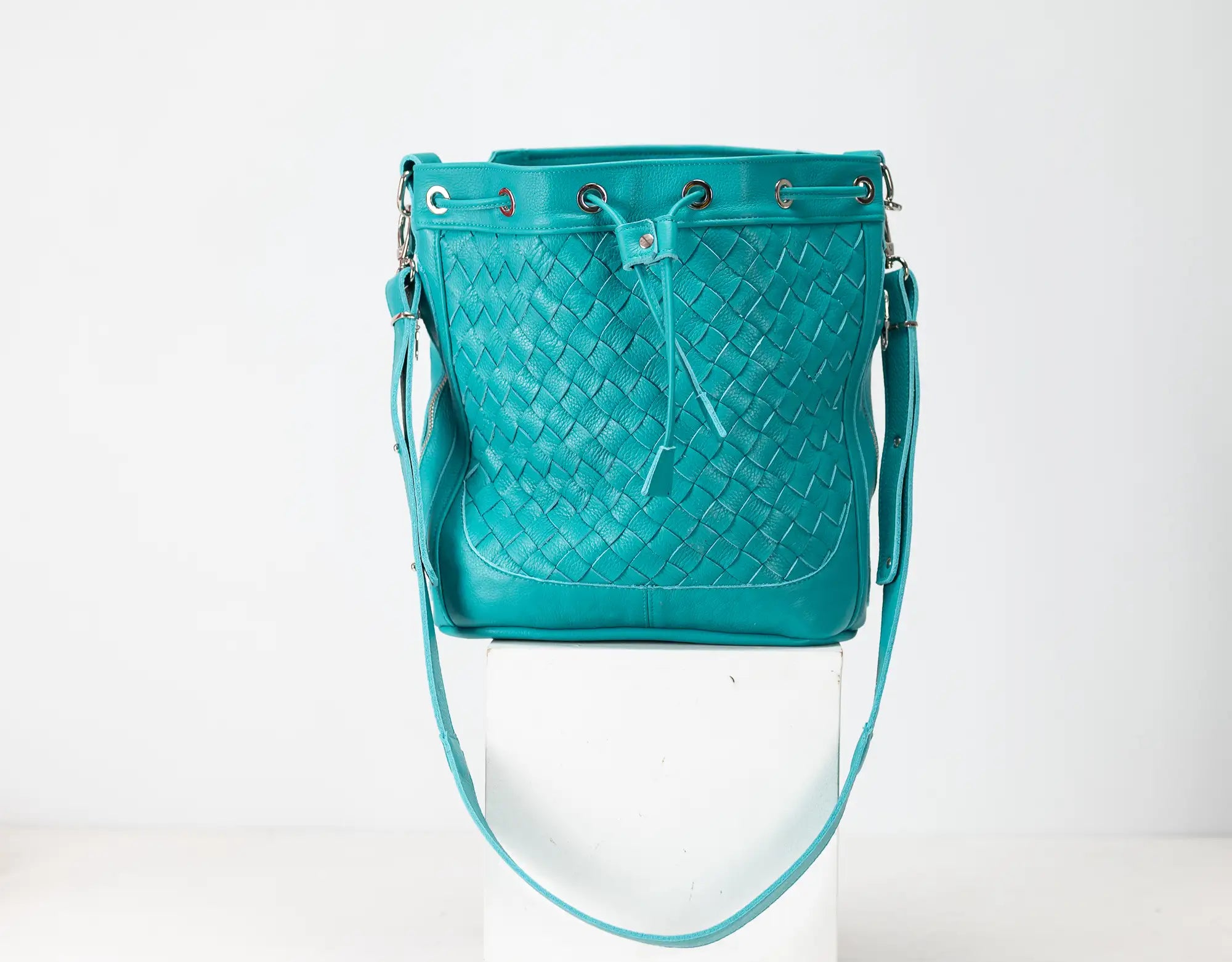 Teal woven handbag on a white background
