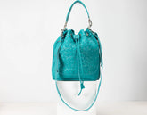 Turquoise woven handbag on a white background