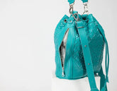 Turquoise woven leather bag with a drawstring on a white background