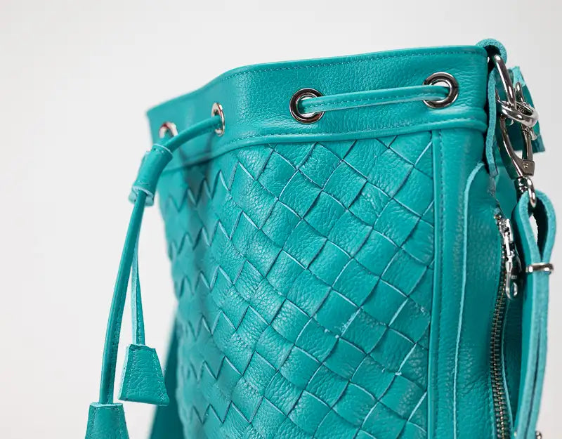 Teal woven leather bucket bag with drawstring on a white background