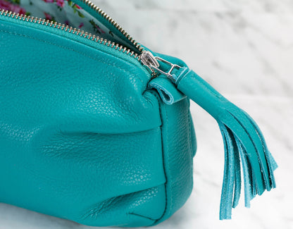 Turquoise handbag with a tassel detail on a light background