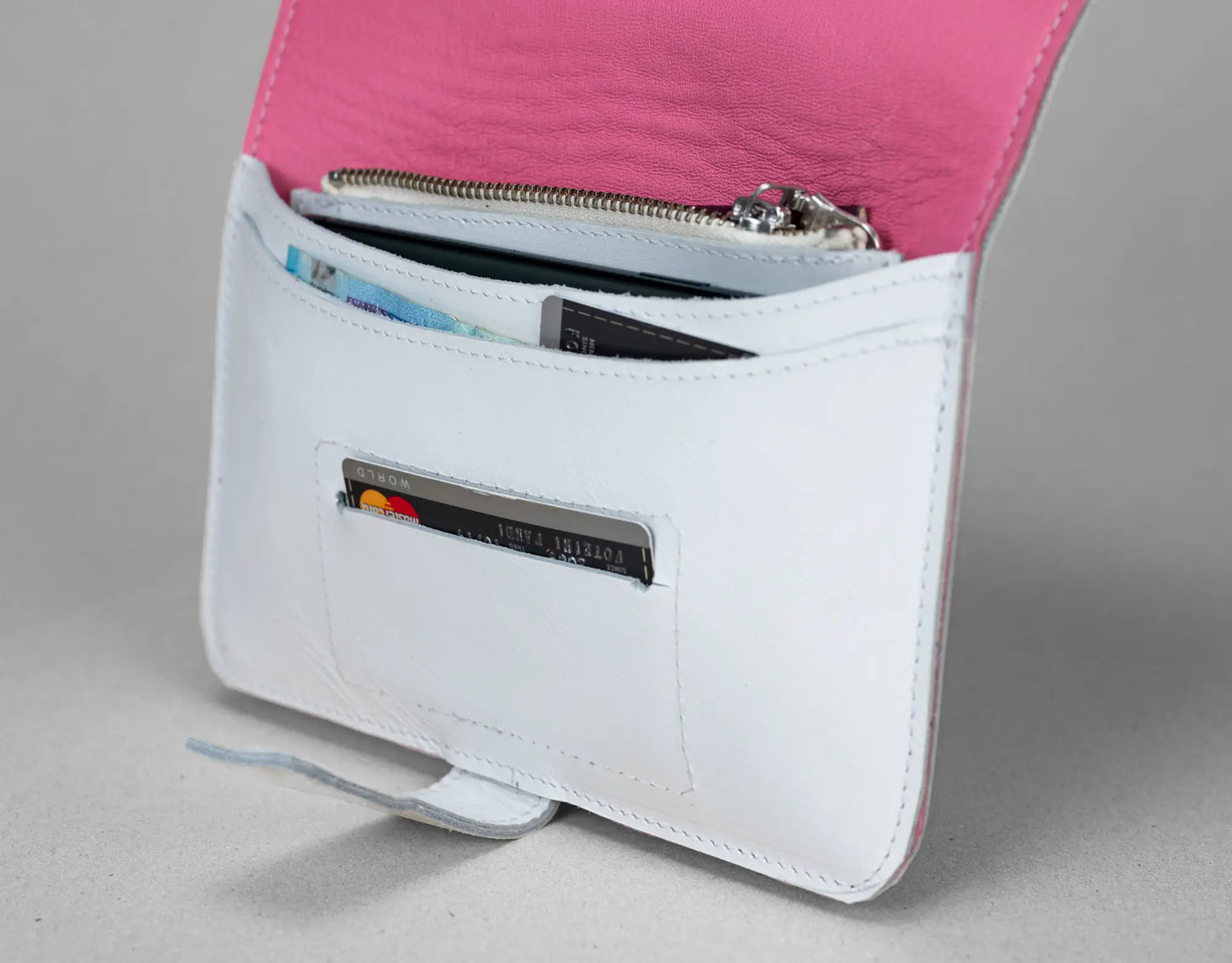 White wallet with pink interior showing card slots on a gray background