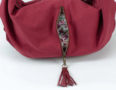 Red handbag with floral zipper pull on a white background