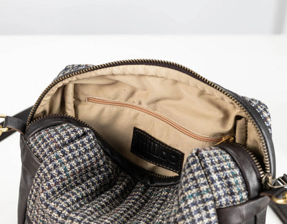 Close-up of an open handbag showing the interior lining, zipper, and a multicolor houndstooth patterned fabric exterior with dark brown leather trim.