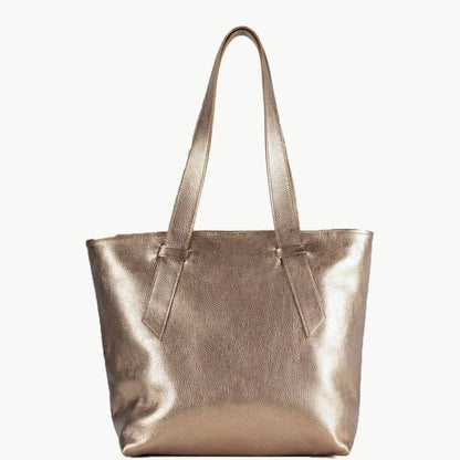 A metallic rose gold leather tote bag with two shoulder straps, shown against a plain off-white background.