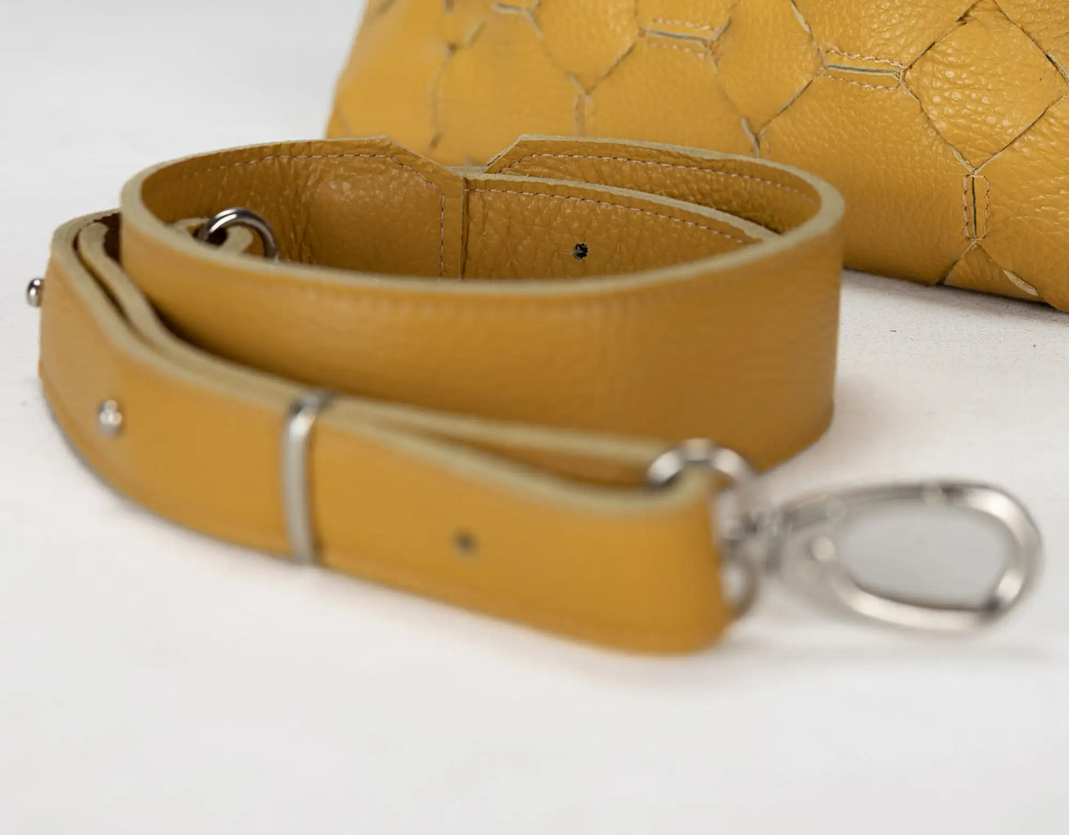 Yellow leather strap with metal clasp on a white background