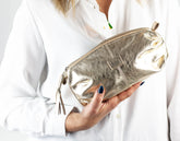 Gold pouch held by a person wearing a white shirt